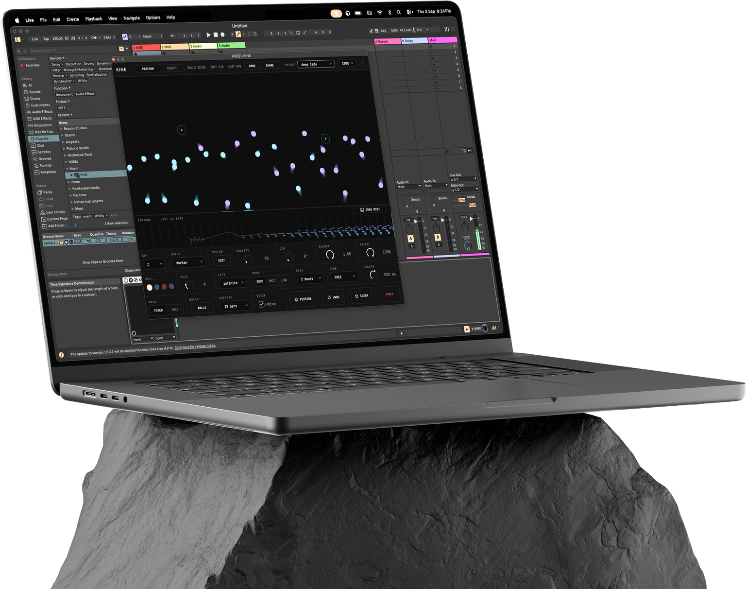 Kine running in Ableton Live on an aluminium laptop resting on a textured grey rock.